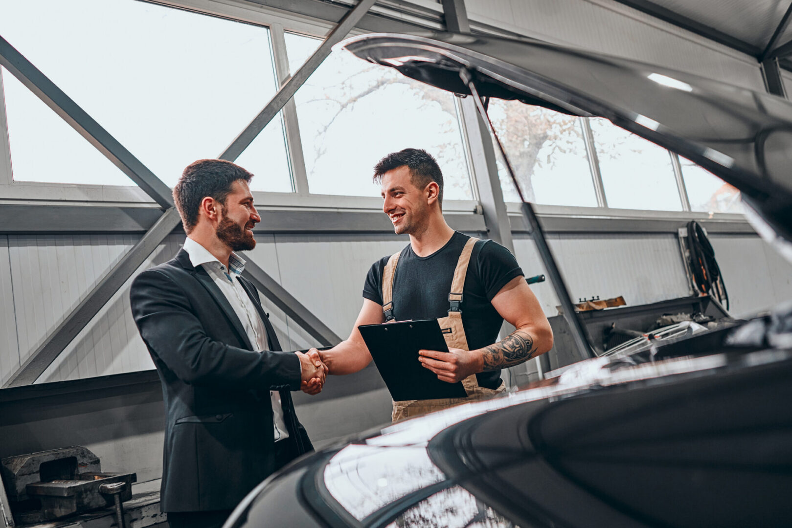 Mechanic and customer shaking hands beside car
