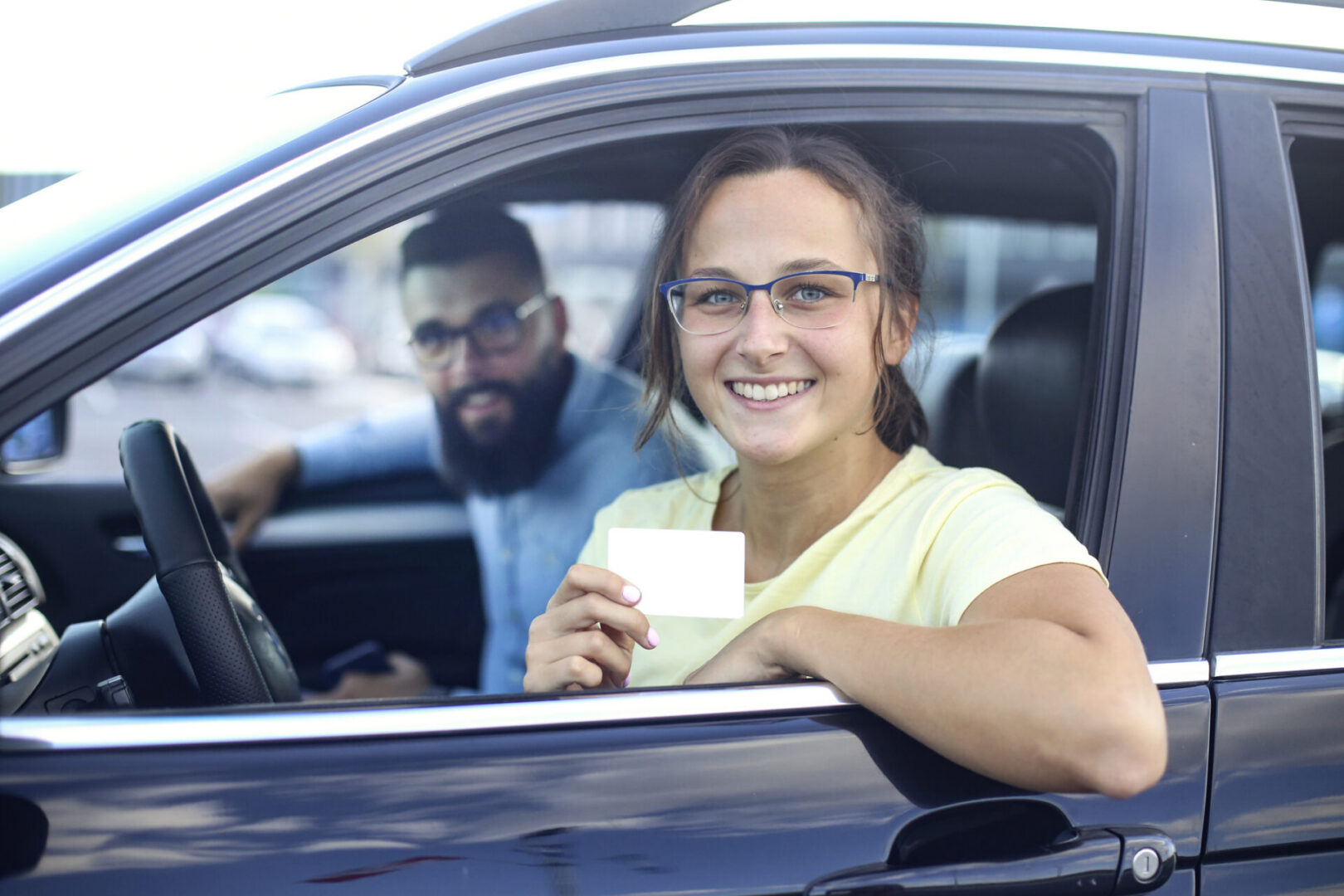 Young woman learning how to drive a car. About 20 years old, Caucasian female and a mid adult male driving instructor.