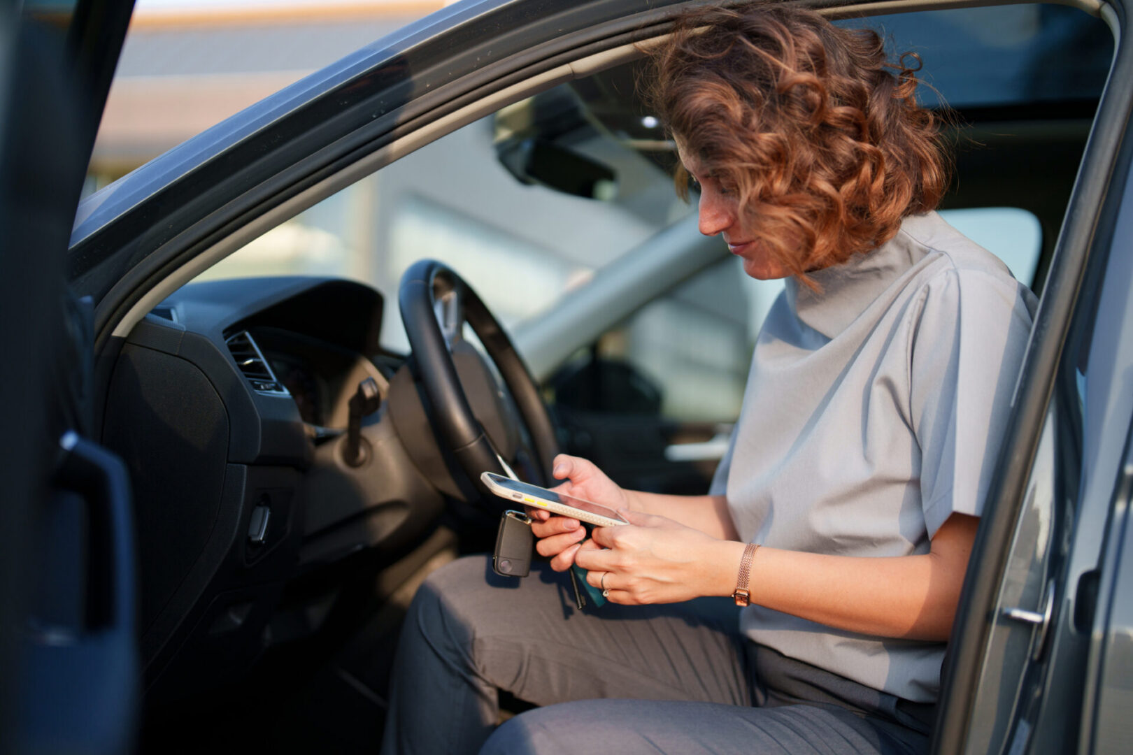Woman in car checking phone and keys